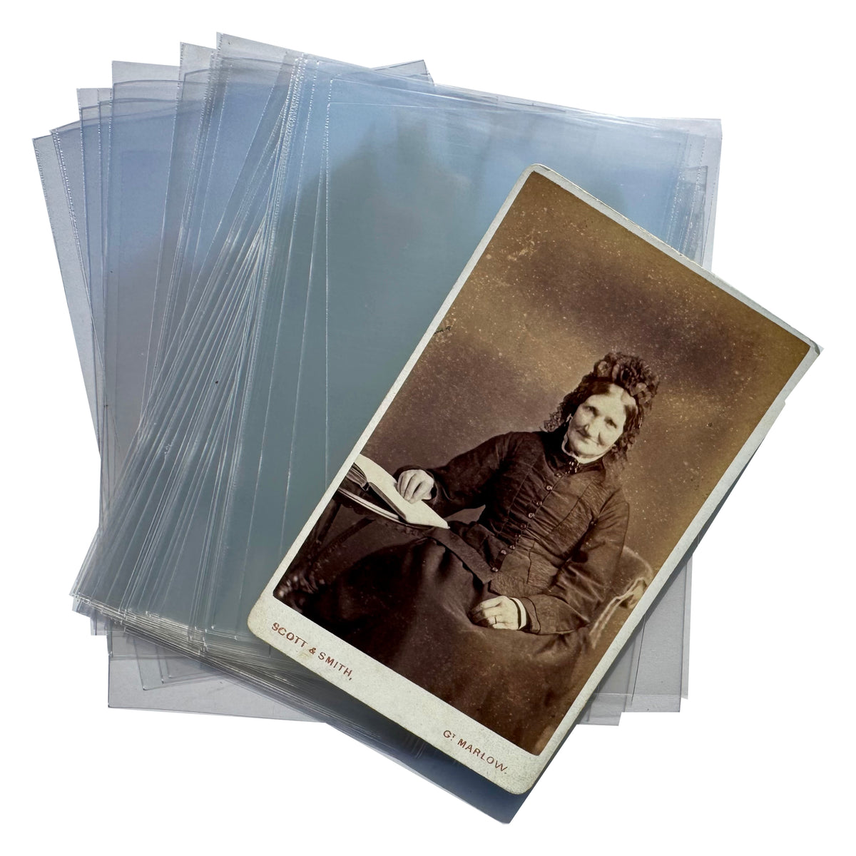 A stack of translucent plastic protective sleeves with one sleeve holding a vintage sepia-toned portrait photograph, photographed on a plain white background.