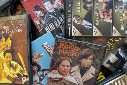 Collection of vintage movie posters and DVD cases on a table.